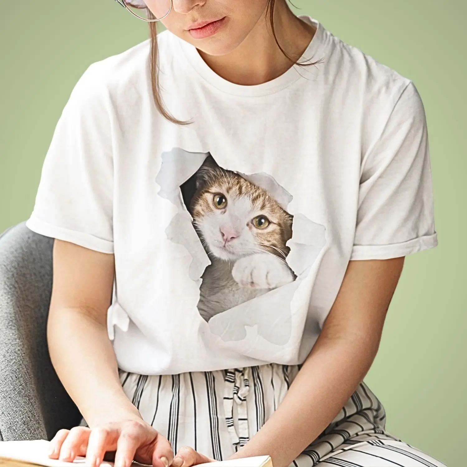 Camiseta com estampa artística de gato que parece estar saindo de dentro de um rasgo no centro.