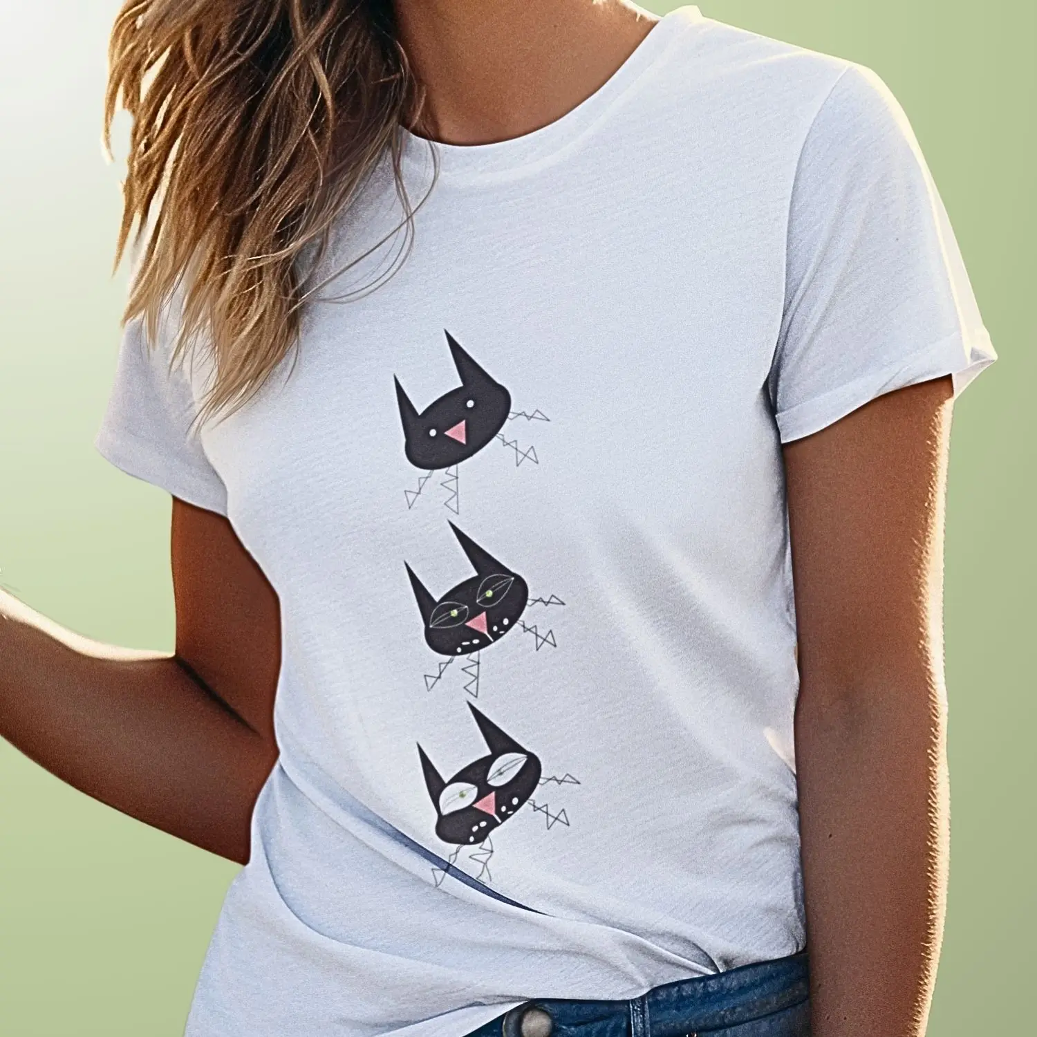 Camiseta com estampa de desenho da carinha de uma gata preta que aparece três vezes: jovem, madura e mais velha